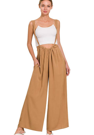 Woman wearing a white top and deep camel pants on a white background